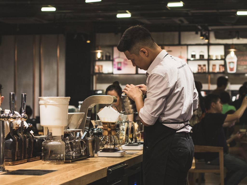 Male barista behind counter at specialty coffee shop