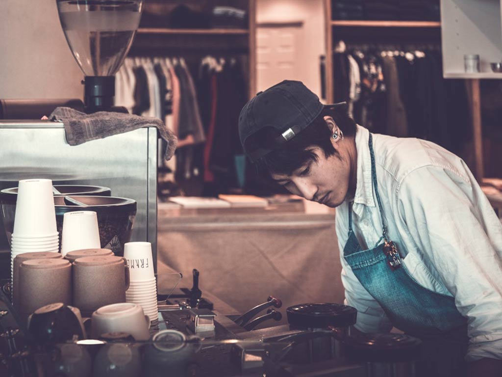 Student working at coffee machine in mixed retail outlet