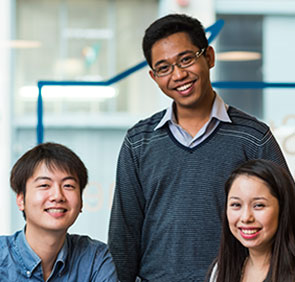 A group of three international students smiling