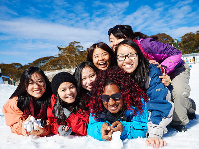 a pile of laughing international students in the snow