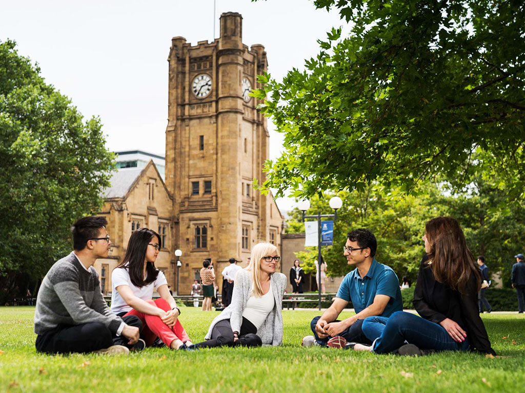 international students on lawn with sandstone university behind